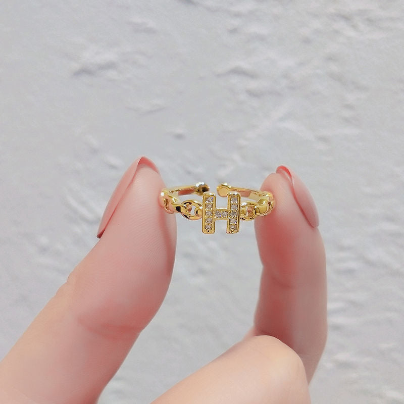 Anello minimalista con lettera H in ottone placcato oro con dettagli in strass e fascia aperta regolabile