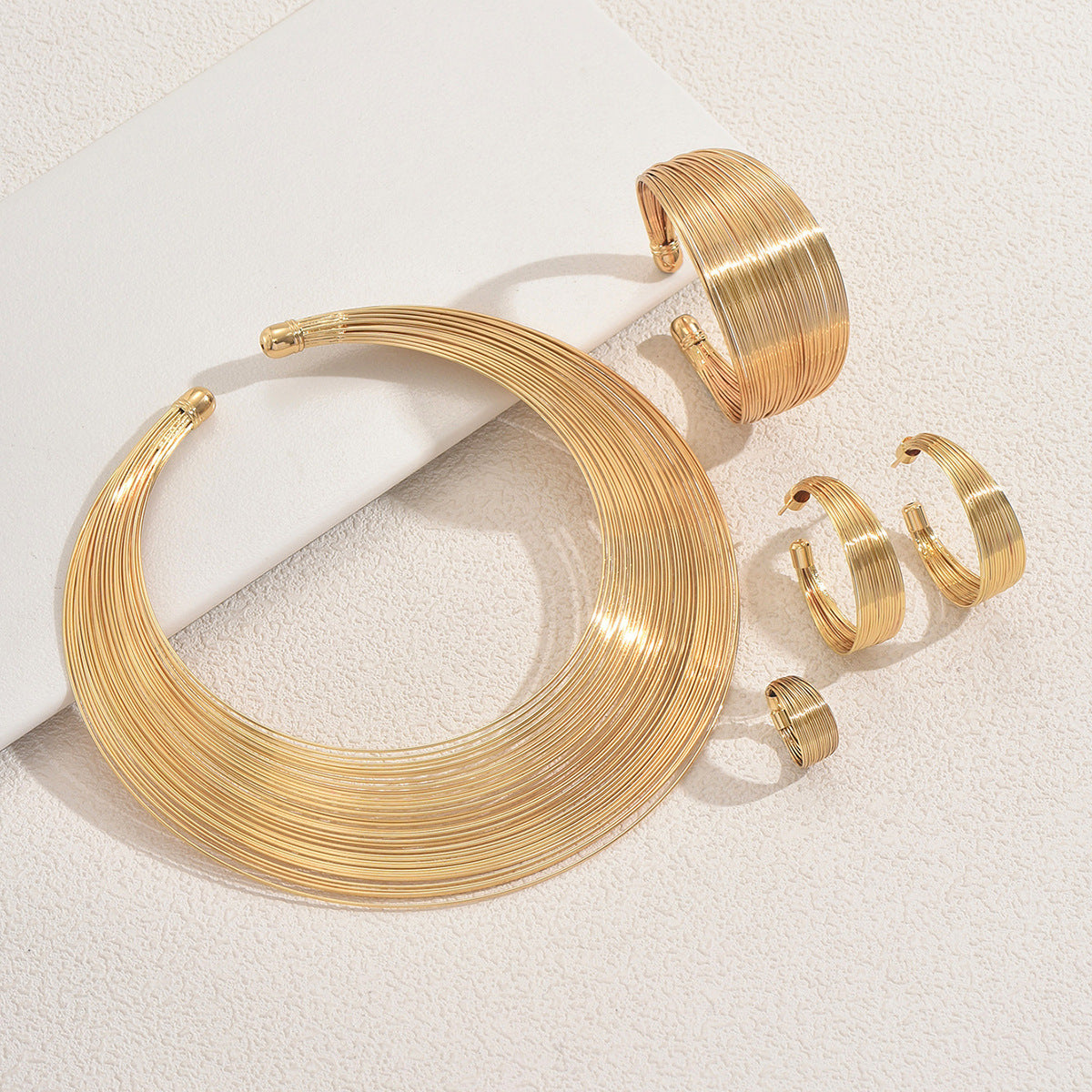 Conjunto de collar de metal multicapa con diseño de líneas geométricas, pulsera ajustable y pendientes para mujer