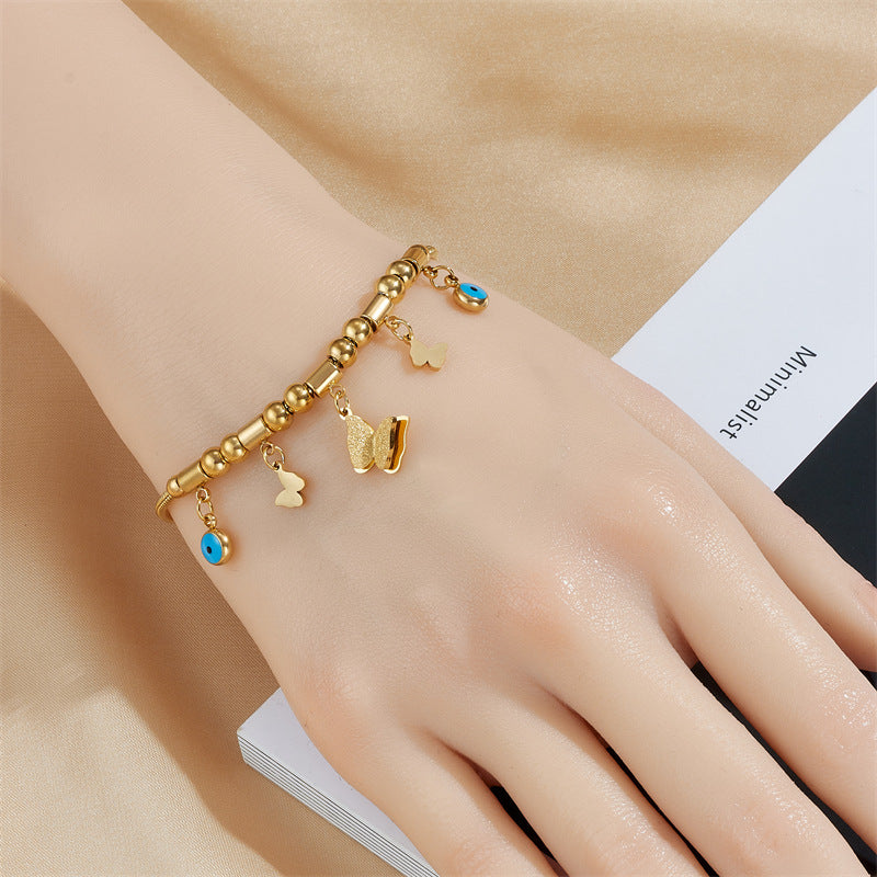 Elegante bracciale con ciondolo a farfalla in acciaio al titanio, perline geometriche e occhi smaltati blu per donna