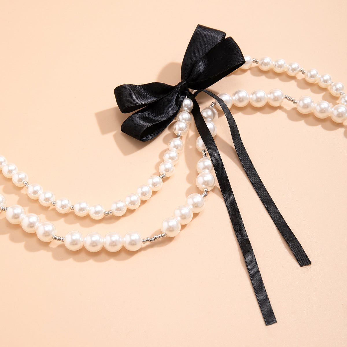 Collana di perle vintage chic con fiocco e dettagli geometrici su catena di perline