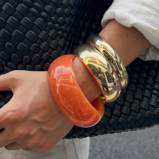 Bracciale rigido da donna minimalista e geometrico in acrilico e metallo, con superficie curva lucida e finitura placcata