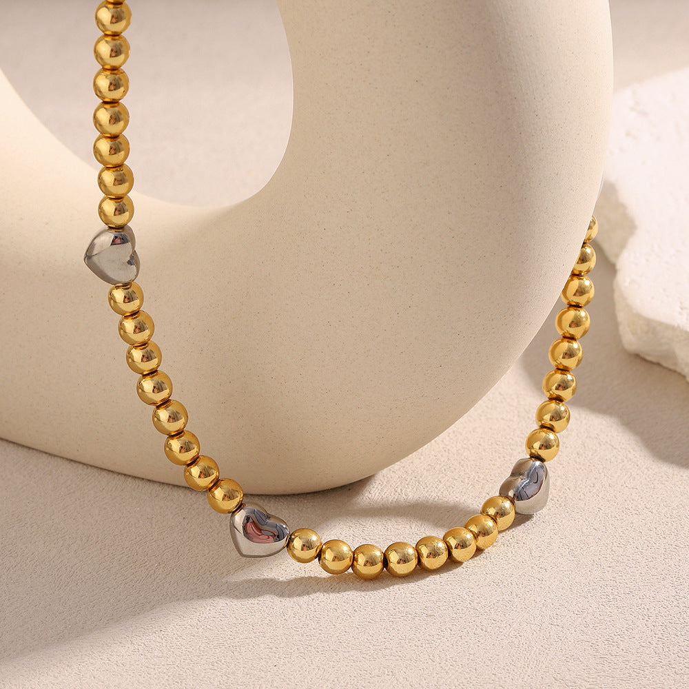 Collar de acero inoxidable minimalista con forma de corazón, chapado en oro de 18 quilates y detalle de cuentas.