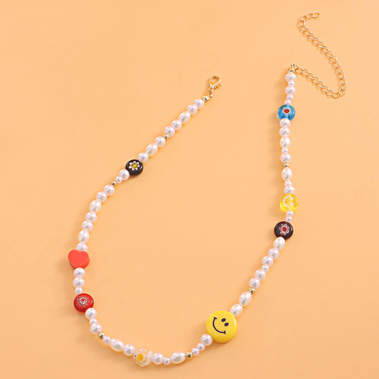 Collana in acrilico con faccina gialla e ciondolo a forma di cuore in argilla polimerica rossa e fiore in vetro su catena in filo di nylon trasparente