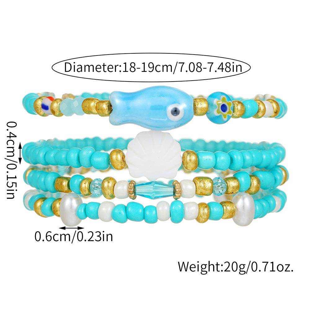 Pulsera bohemia de vacaciones en la playa con abalorios de peces y conchas de cerámica en un hilo de cuentas multicapa
