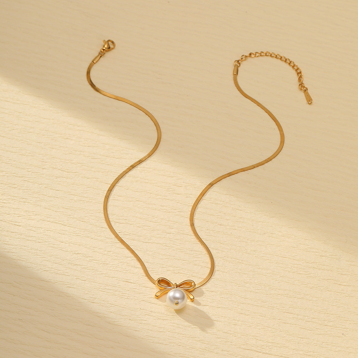 Collar minimalista de acero de titanio con forma de lazo para mujer, con acabado galvanizado y detalle de perlas