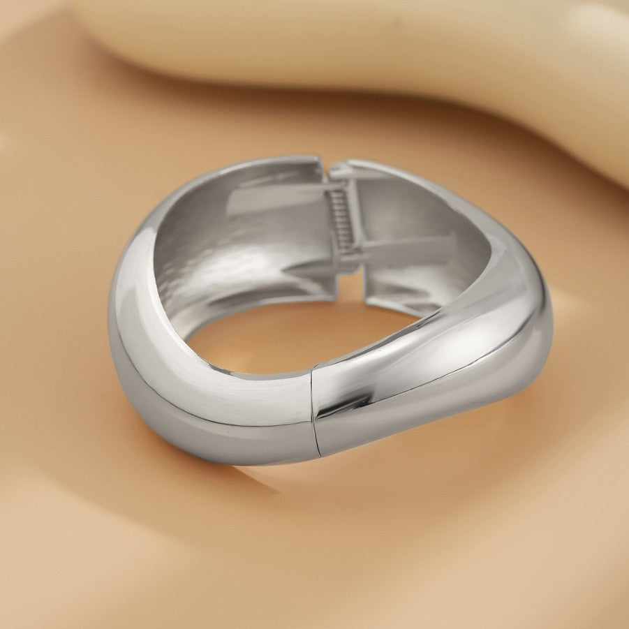 Bracciale rigido da donna in metallo audace con design geometrico, superficie lucida e finitura placcata