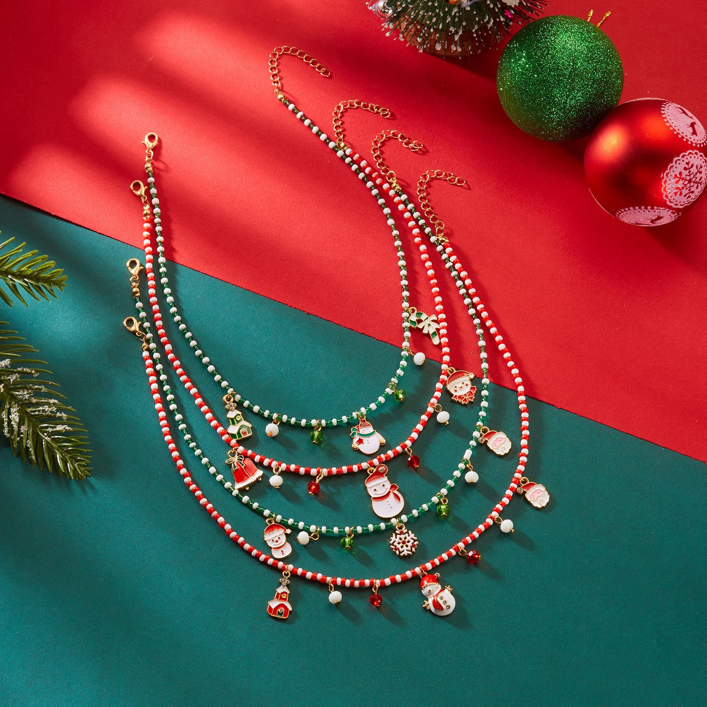 Collana in lega a tema natalizio con ciondolo a forma di Babbo Natale, campanella, casa innevata e fiocco di neve in stile festivo