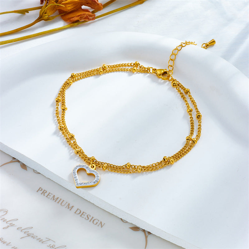 Cavigliera minimalista in acciaio al titanio a forma di cuore con intarsio di strass e design a doppia catena