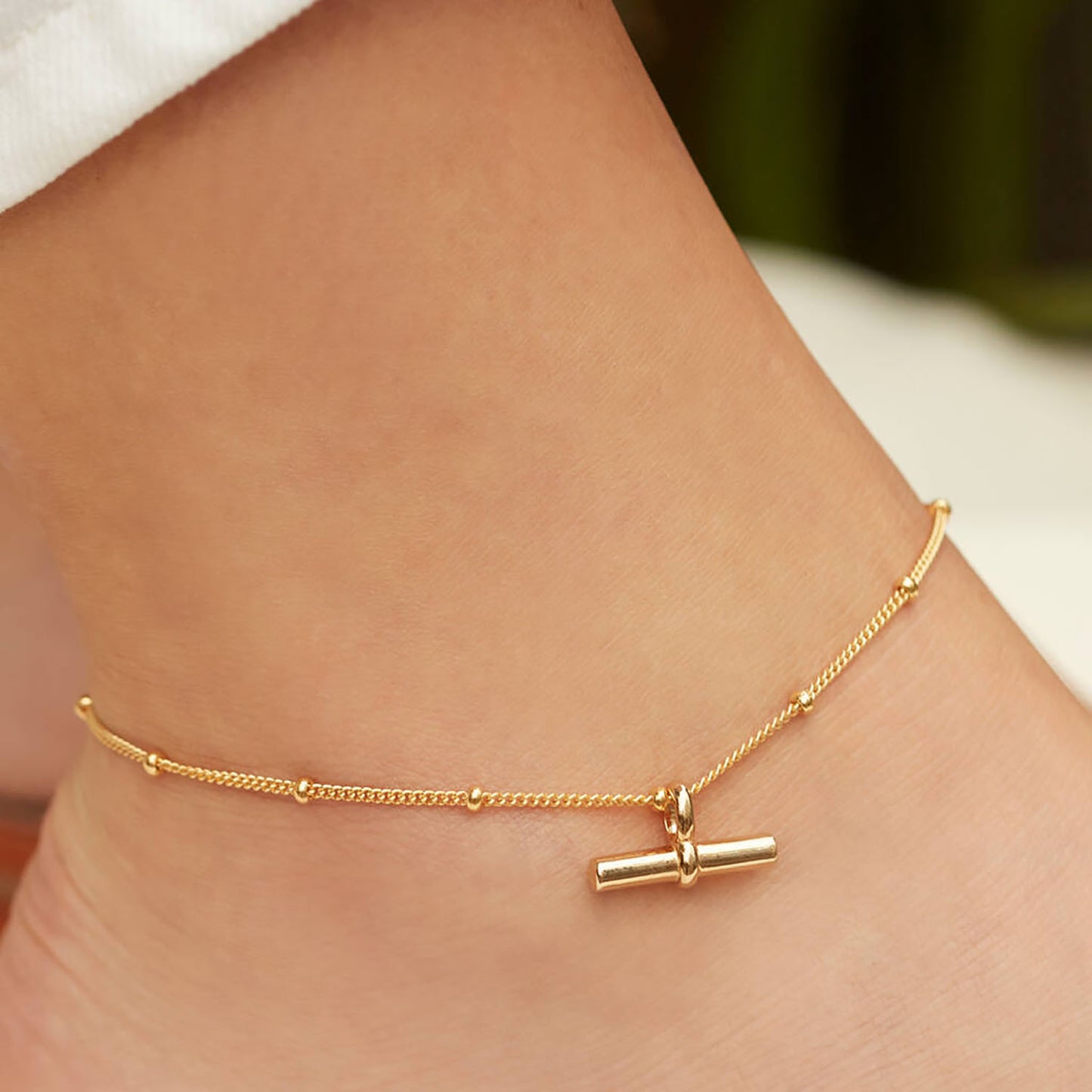 Tobillera minimalista geométrica de titanio y acero con colgante de barra en T chapado en oro de 18K y cadena de cuentas.