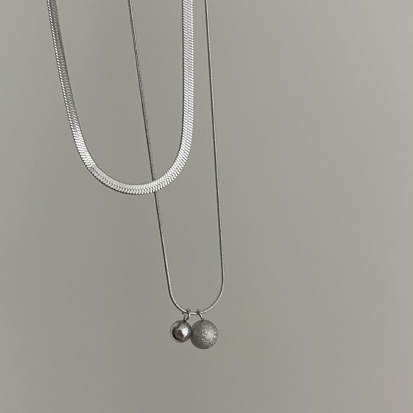 Collana a catena a serpente a doppio strato in acciaio al titanio minimalista da donna con pendenti sferici piccoli e grandi e perline portafortuna