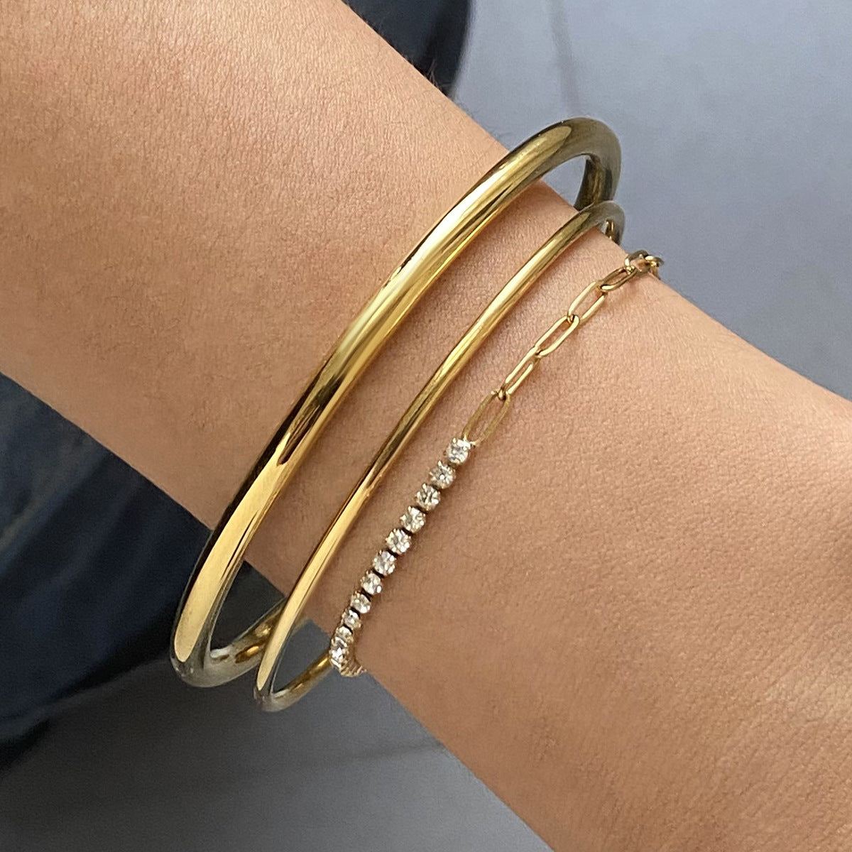 Brazalete minimalista de acero inoxidable con diseño geométrico, detalles de pedrería y acabado chapado