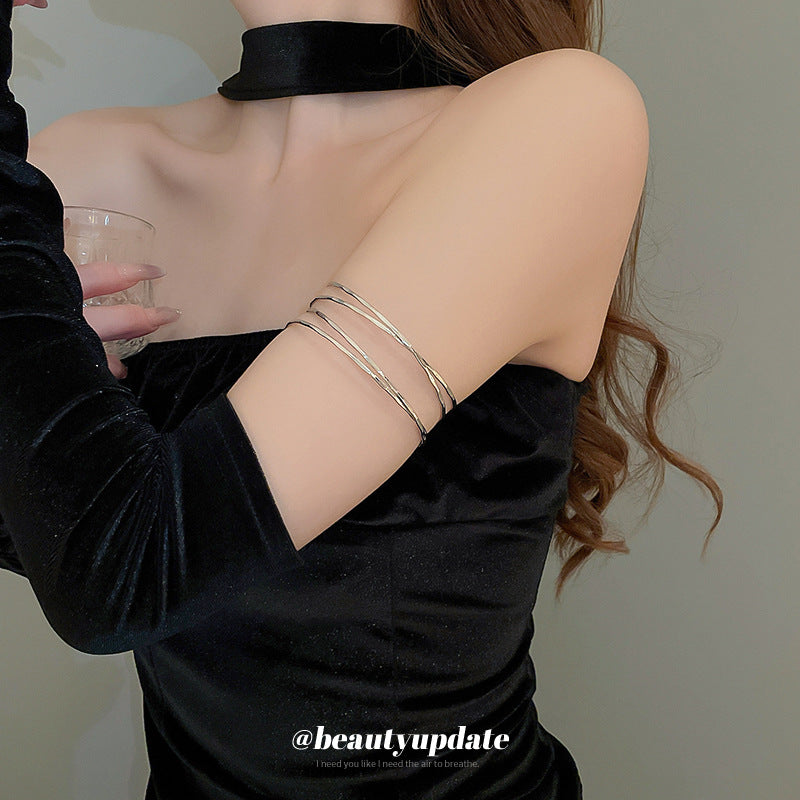 Bracciale rigido in metallo avvolto da linee geometriche irregolari, finitura placcata, stile minimalista, per un look da ufficio alla moda