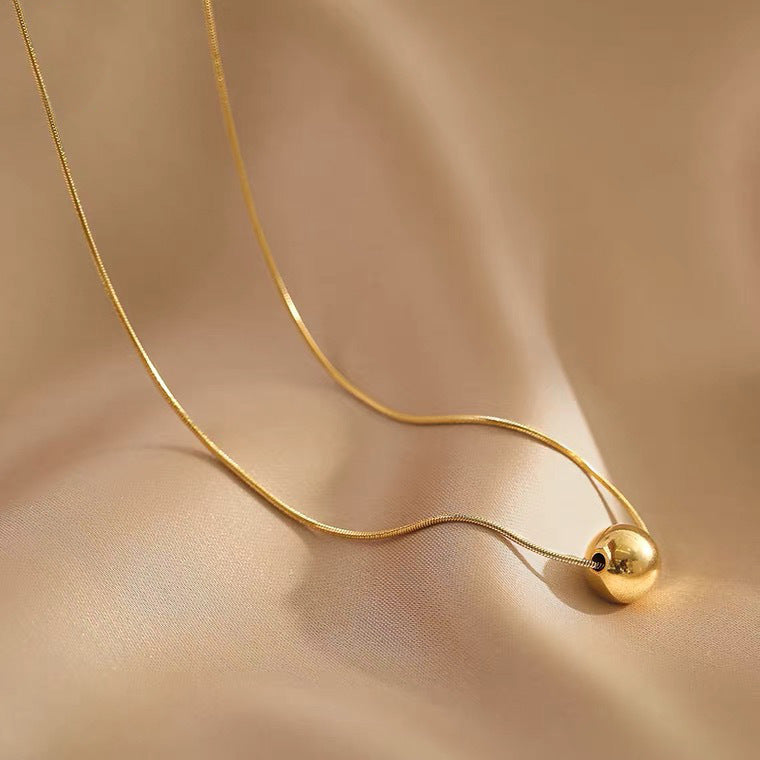 Collana da donna minimalista con pendente a sfera in acciaio al titanio con placcatura in oro e catena a serpente