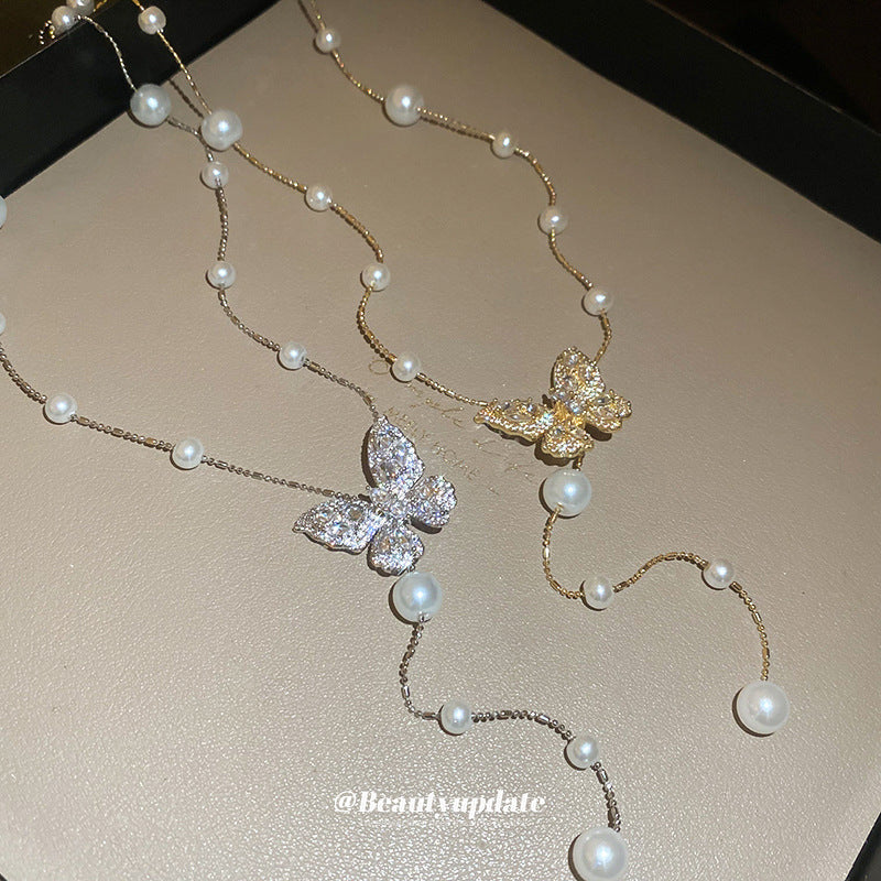 Collana con ciondolo a farfalla in zirconi placcato oro, stile dolce e minimalista, con inserti in perle e dettagli sfrangiati da donna