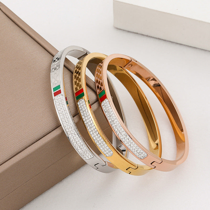Pulsera minimalista de acero de titanio con incrustaciones de pedrería roja y verde, bañada en oro rosa para mujer