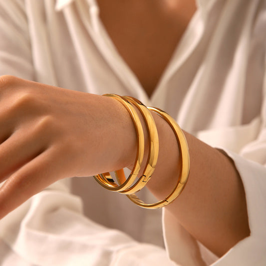 Bracciale a fascia rigida minimalista in acciaio al titanio con bordi arrotondati lucidi e placcatura in oro da donna