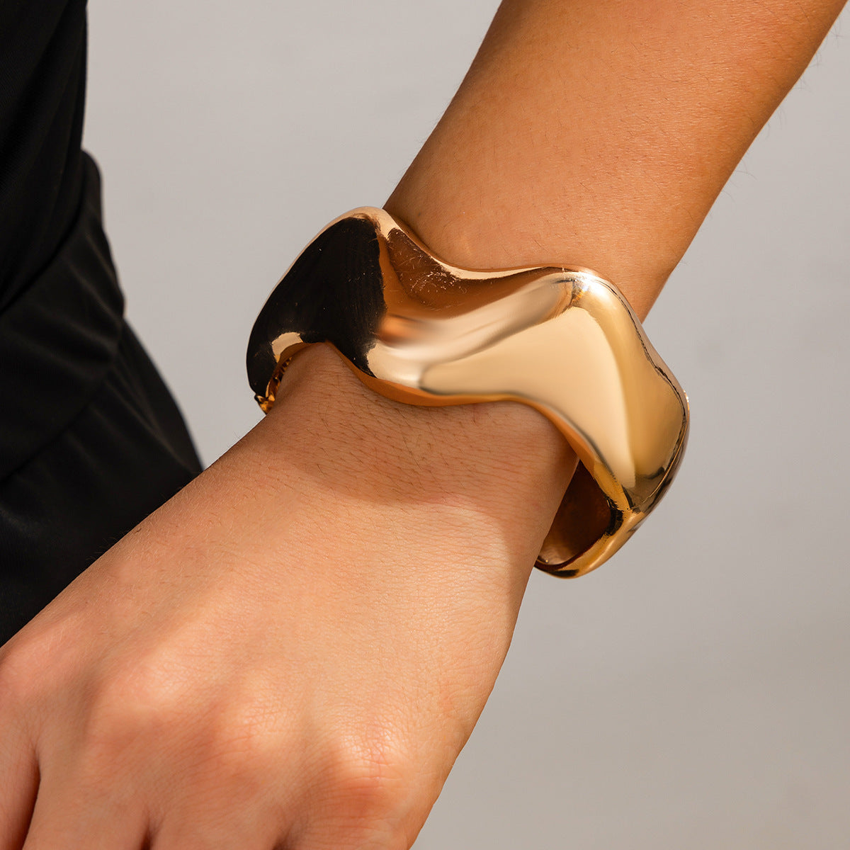 Bracciale rigido da donna in metallo audace con design geometrico, superficie lucida e finitura placcata