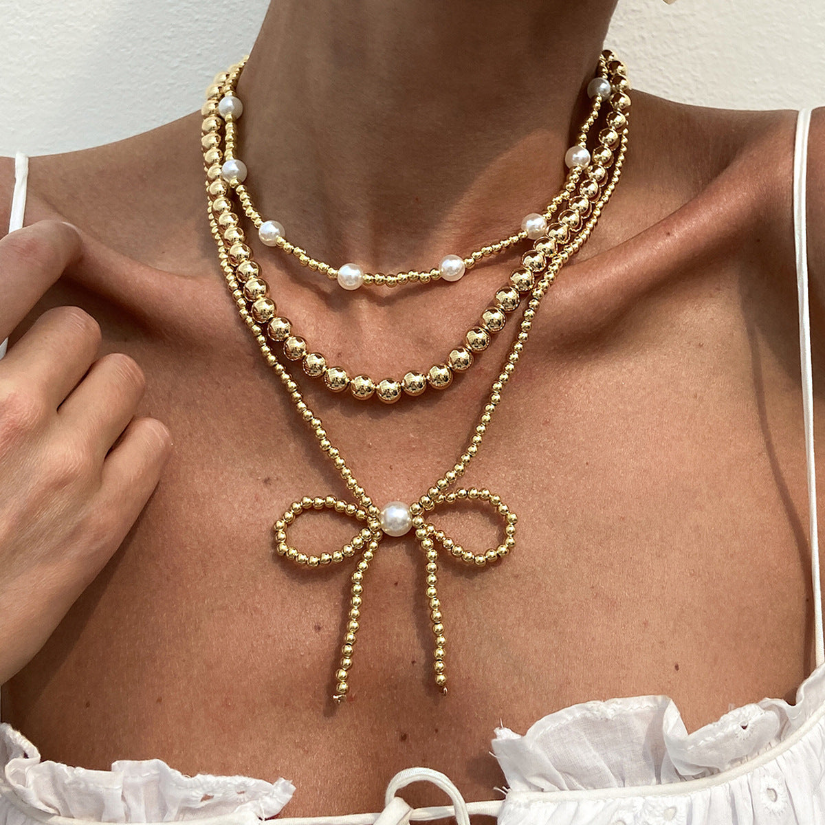 Collana da donna minimalista a forma di fiocco con perle finte e CCB, catena a sfere con perline e design multistrato