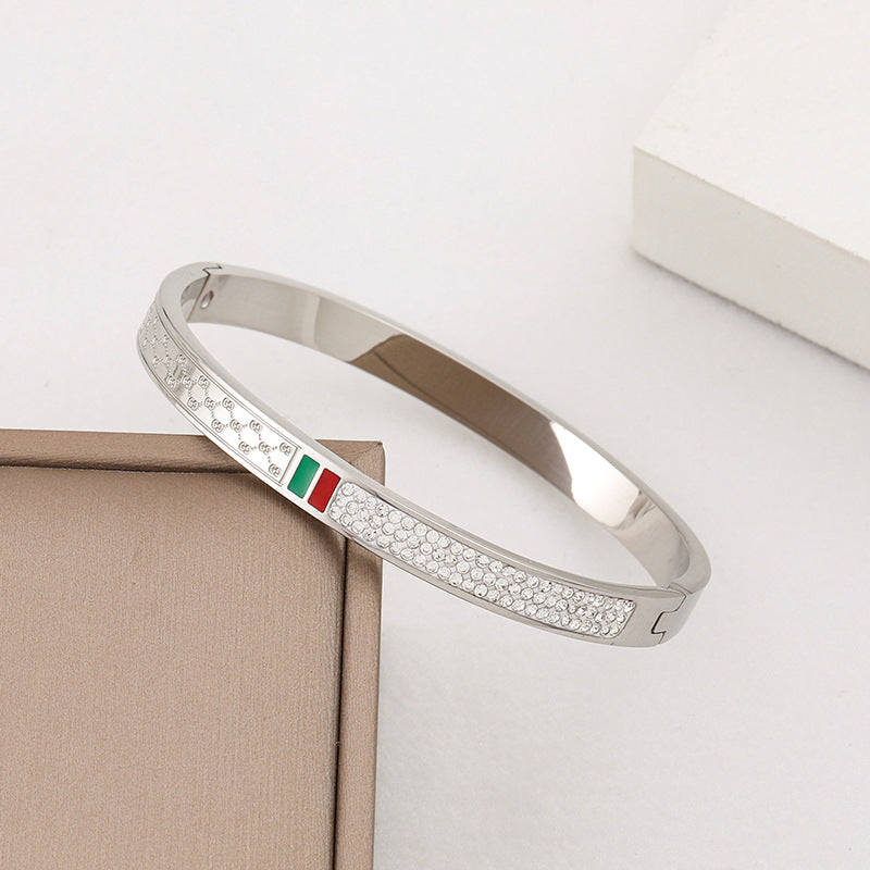 Pulsera minimalista de acero de titanio con incrustaciones de pedrería roja y verde, bañada en oro rosa para mujer