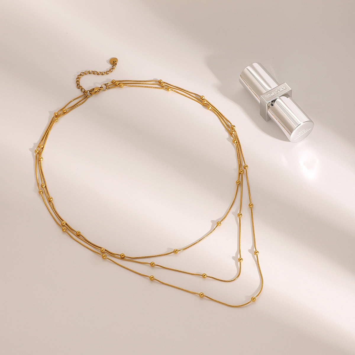 Collana da donna a più strati con perle dorate in acciaio inossidabile placcato e acciaio al titanio, con dettagli geometrici e linee delicate