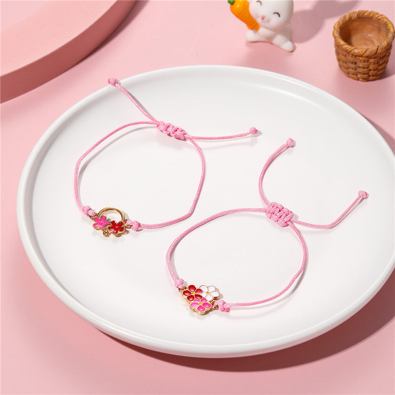 Pulsera infantil de cuerda trenzada con motivo floral y acabado esmaltado en metal de aleación