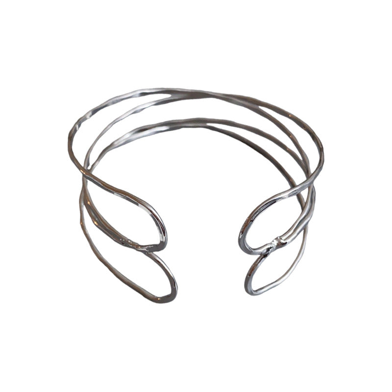 Bracciale rigido in metallo avvolto da linee geometriche irregolari, finitura placcata, stile minimalista, per un look da ufficio alla moda