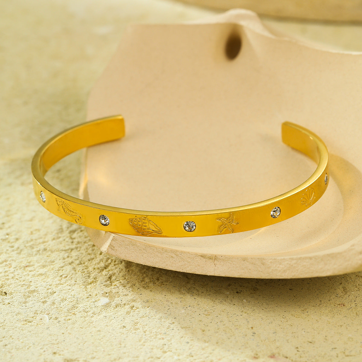 Brazalete abierto de acero de titanio con diseño geométrico, inspirado en el océano, con incrustaciones de pedrería y acabado chapado