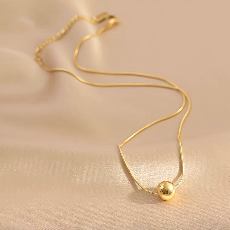Collana da donna minimalista con pendente a sfera in acciaio al titanio con placcatura in oro e catena a serpente