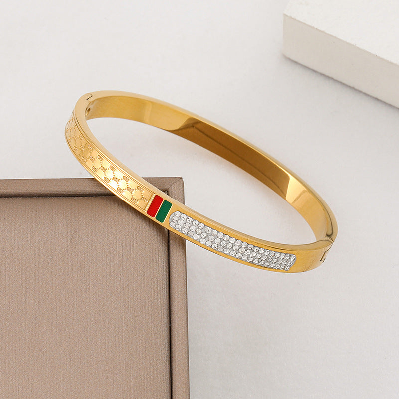 Pulsera minimalista de acero de titanio con incrustaciones de pedrería roja y verde, bañada en oro rosa para mujer