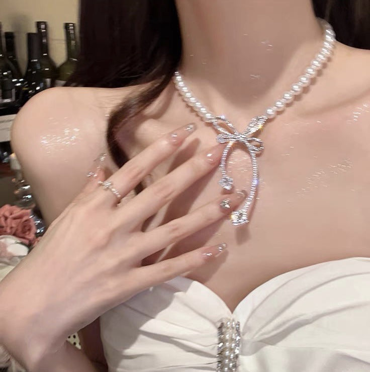 Elegante collar con colgante de lazo de diamantes de imitación y detalles de nácar perlado para mujer — Delicada cadena para clavícula en estilo de lujo minimalista y a la moda