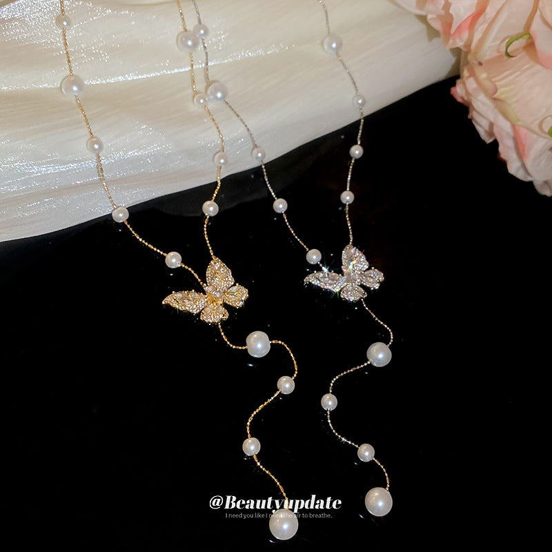 Collana con ciondolo a farfalla in zirconi placcato oro, stile dolce e minimalista, con inserti in perle e dettagli sfrangiati da donna