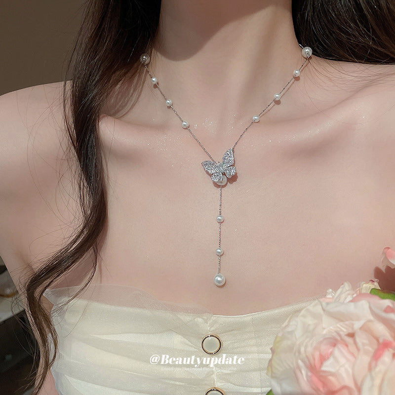 Collana con ciondolo a farfalla in zirconi placcato oro, stile dolce e minimalista, con inserti in perle e dettagli sfrangiati da donna