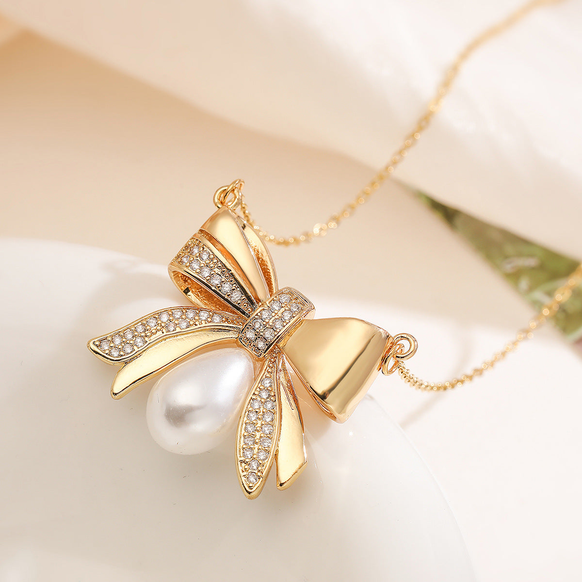 Collana girocollo da donna con ciondolo a fiocco placcato in oro 18 carati su base in rame, con zirconi e perle.