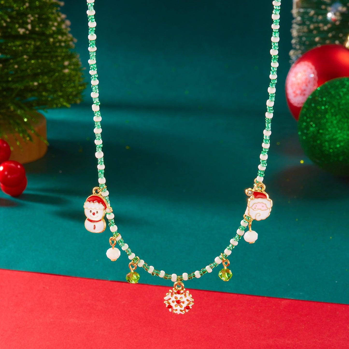Collana in lega a tema natalizio con ciondolo a forma di Babbo Natale, campanella, casa innevata e fiocco di neve in stile festivo