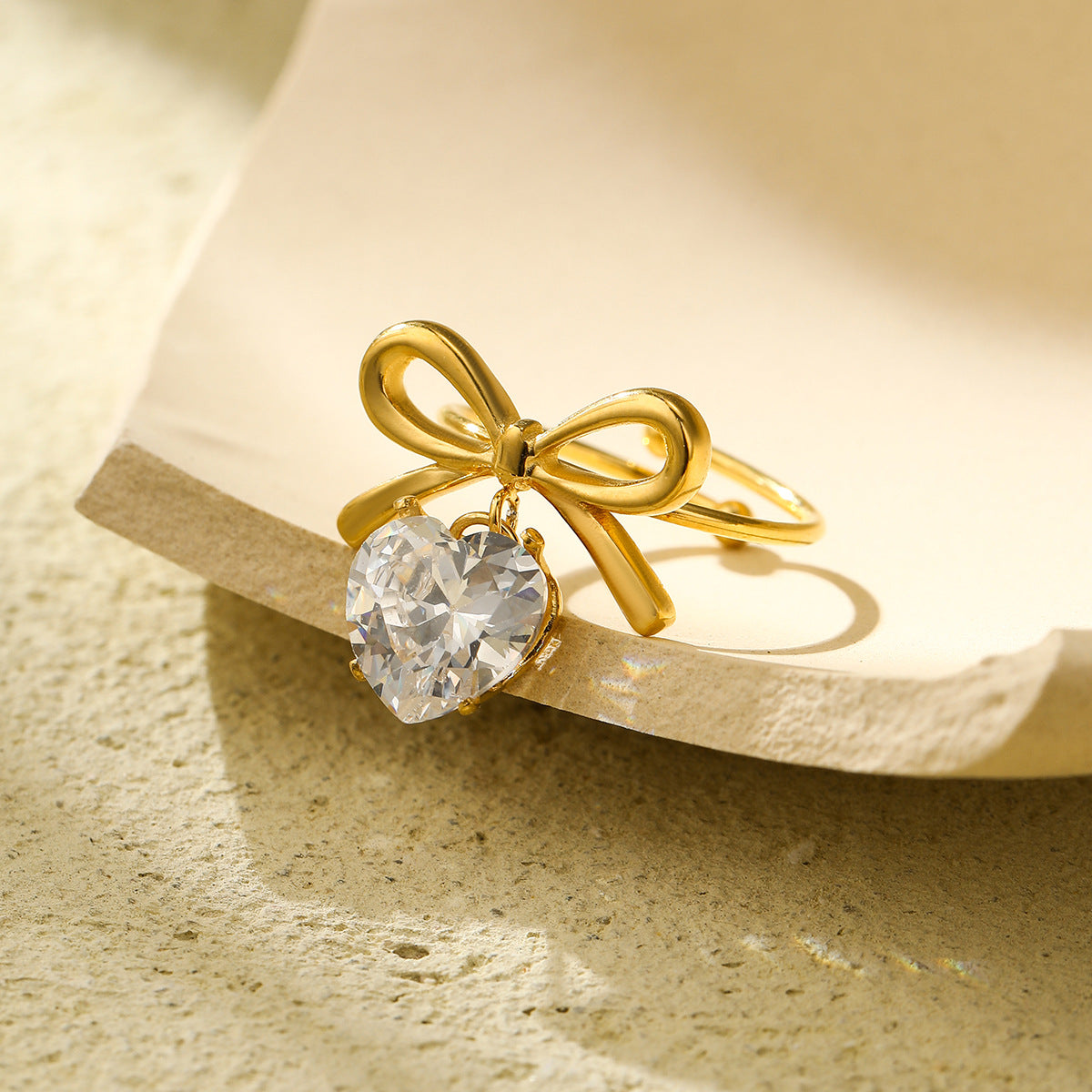 Anillo con colgante de corazón en forma de lazo estilo lujo para mujer, hecho de acero de titanio con incrustaciones de diamantes de imitación y acabado chapado