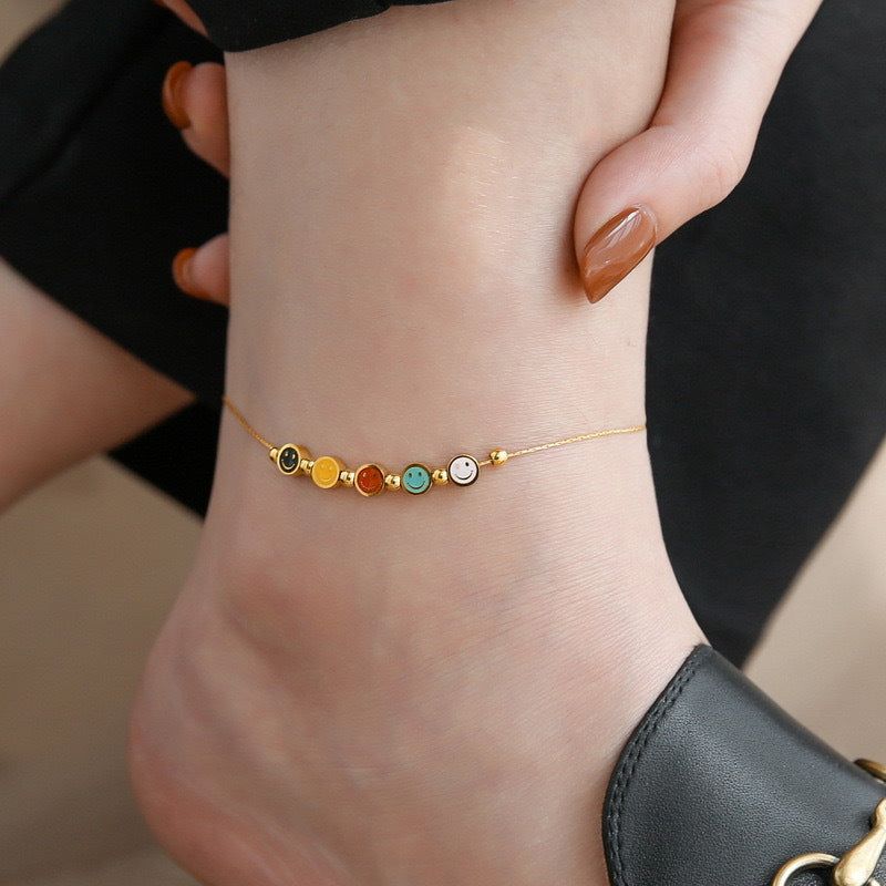 Bracciale da donna in acciaio al titanio con ciondolo sorridente minimalista, finitura smaltata e perline con accenti in oro 18 carati