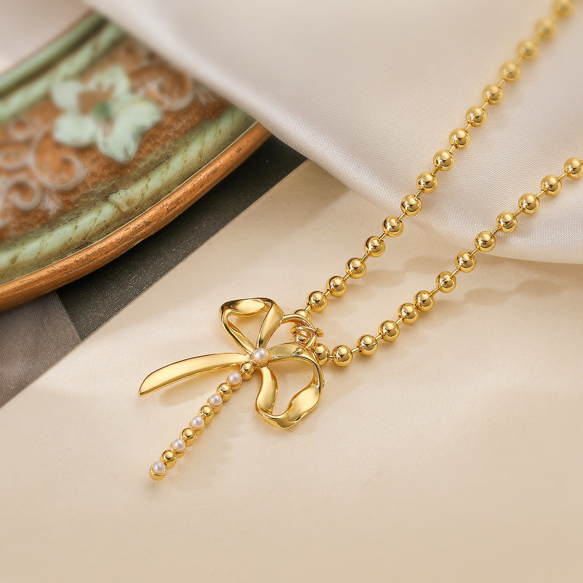 Collana da donna minimalista con fiocco, intarsio di perle e catena placcata oro in rame