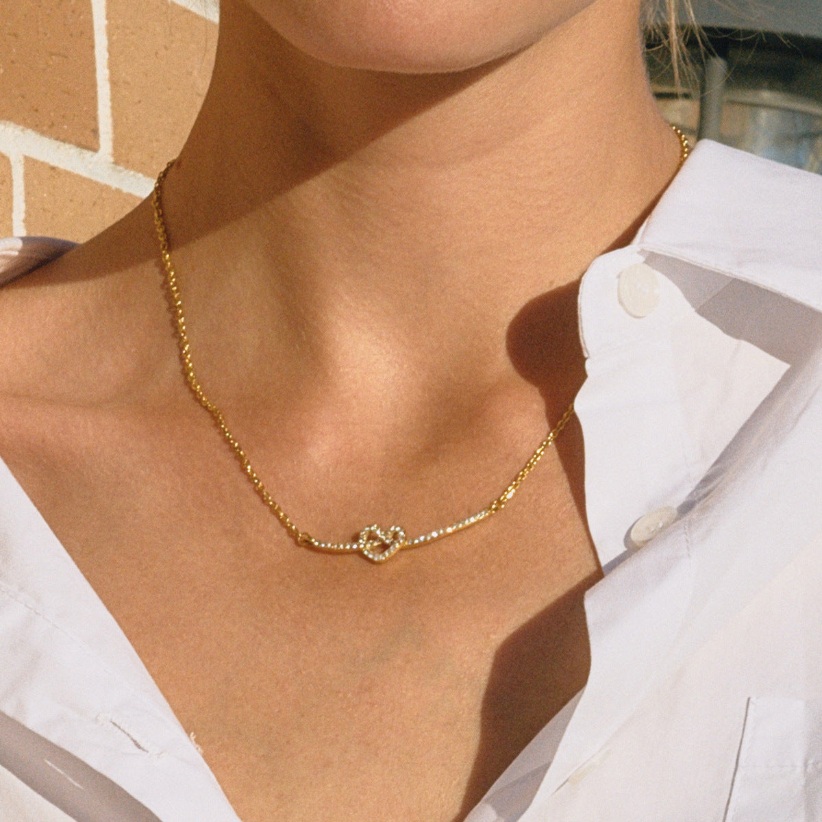 Collana con Ciondolo a Cuore Geometrico Minimalista in Acciaio al Titanio con Intarsio di Zirconi e Placcatura in Oro PVD da Donna