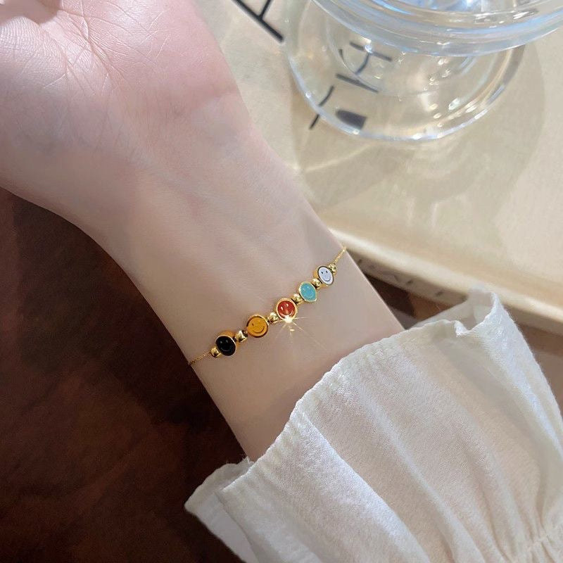 Bracciale da donna in acciaio al titanio con ciondolo sorridente minimalista, finitura smaltata e perline con accenti in oro 18 carati