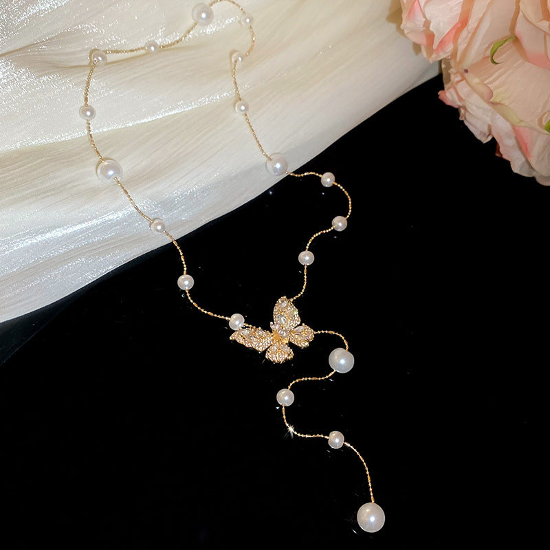 Collana con ciondolo a farfalla in zirconi placcato oro, stile dolce e minimalista, con inserti in perle e dettagli sfrangiati da donna