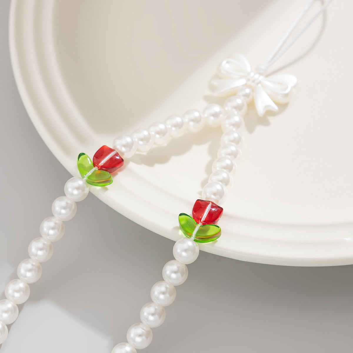 Bonita correa de teléfono con nudo de lazo de tulipán y perlas de imitación para mujeres, accesorio tejido a mano con dulce estilo floral
